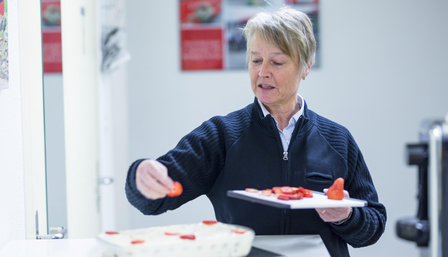 Das Bild zeigt eine Mitarbeiterin, die ein Dessert dekoriert. Die Menschen der ZVB können kennengelernt werden und es kann hinter die Kulissen geblickt werden