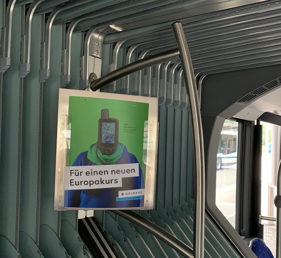 Ein Bushänger mit Werbung im Innenraum des Busses