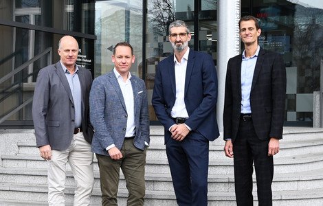 Vier Personen stehen vor Treppe