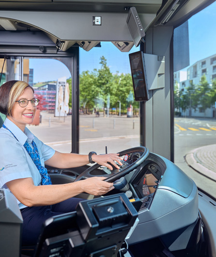 Auf dem Bild ist eine Mitarbeiterin des Fahrdienstes, welche einen Bus fährt, zu sehen