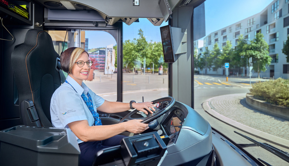 Auf dem Bild ist eine Mitarbeiterin des Fahrdienstes, welche einen Bus fährt, zu sehen