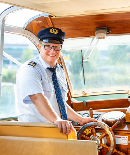 Auf dem Bild ist ein Mitarbeiter der Schifffahrt als Kapitän zu sehen